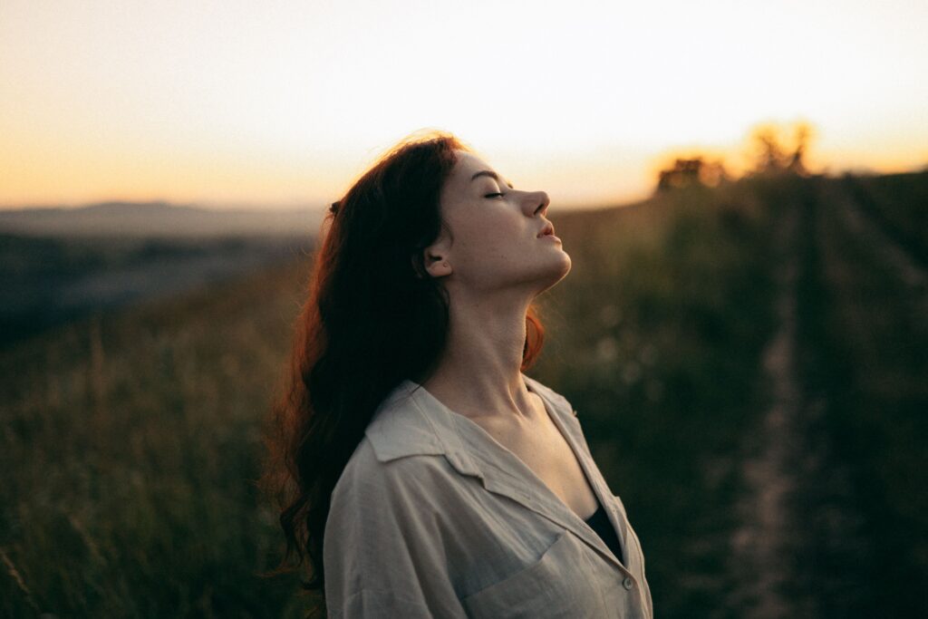 Woman experiencing inner freedom and peace while standing in an open natural landscape